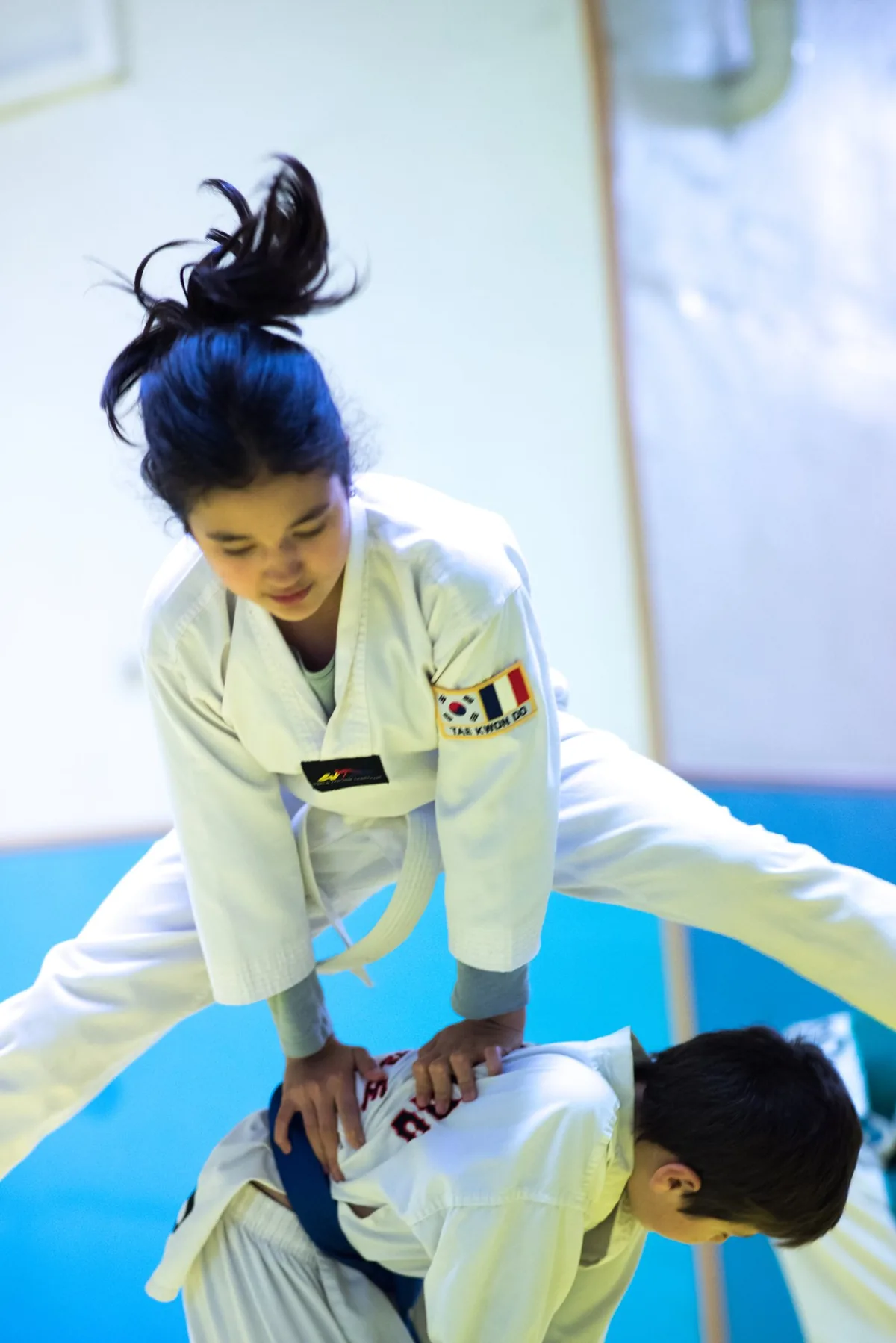 Jeune élève sautant par-dessus un camarade pendant l’échauffement au dojang